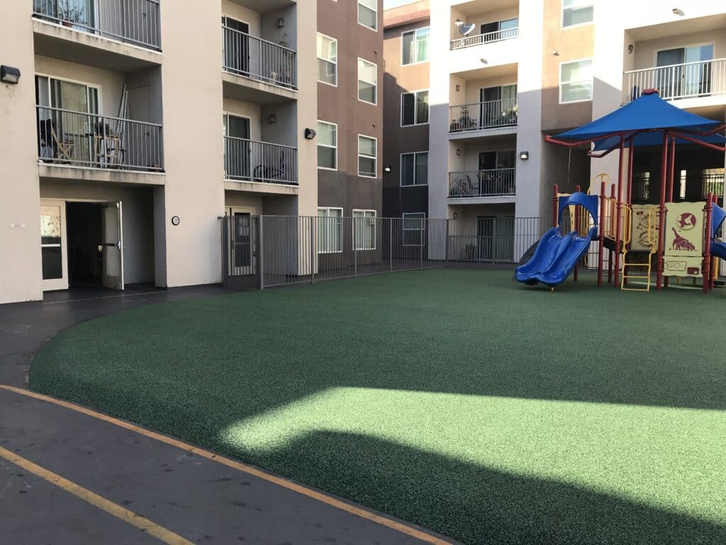 Synthetic turf play area with a play structure in an apartment community courtyard
