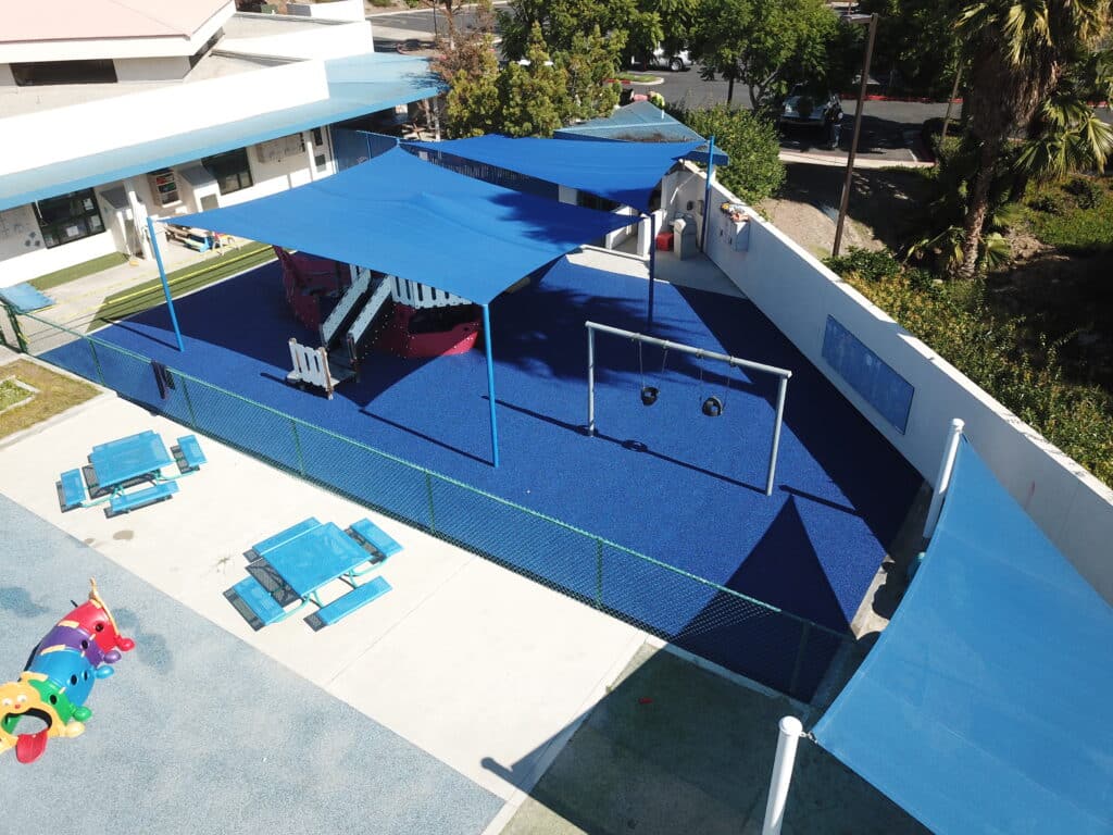 Aerial view of blue poured-in-place rubber under shade sails with picnic tables