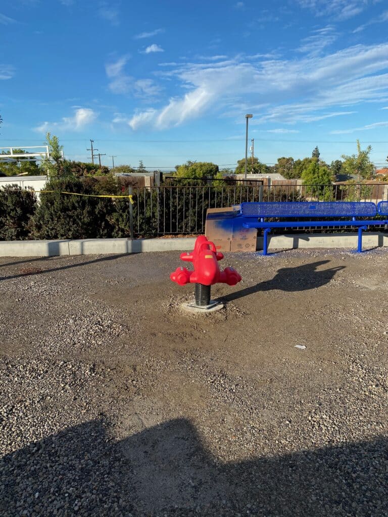 Rubber play surface with a spring rider beside a building
