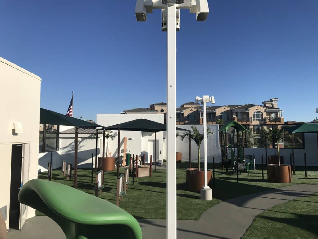 Shade structures over a courtyard play area beside buildings