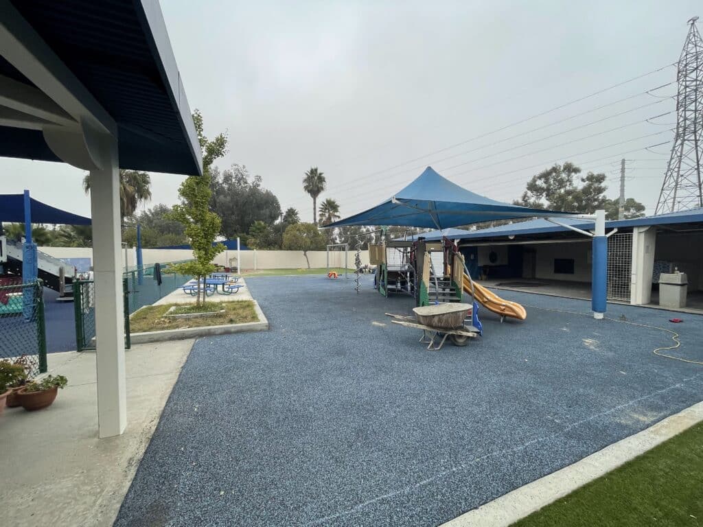 Gray rubber surfacing beside a covered walkway