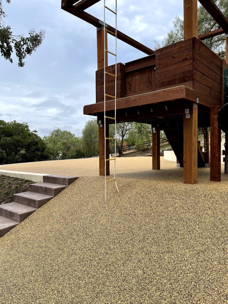 Porous rubber surfacing around the base of a wooden play structure