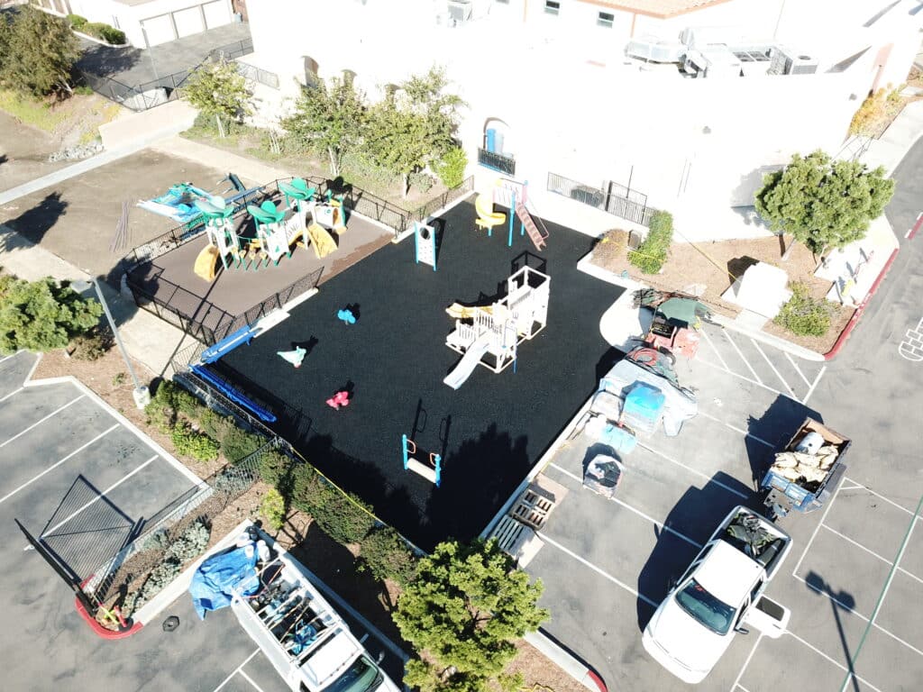 Aerial view of black rubber surfacing in a courtyard with play equipment