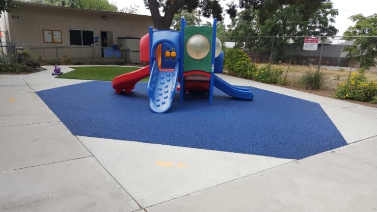 Blue poured-in-place rubber surface around a children's play structure