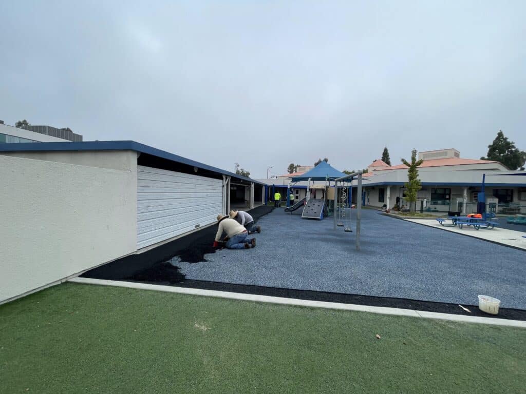 Black rubber surface and synthetic turf in a courtyard between buildings
