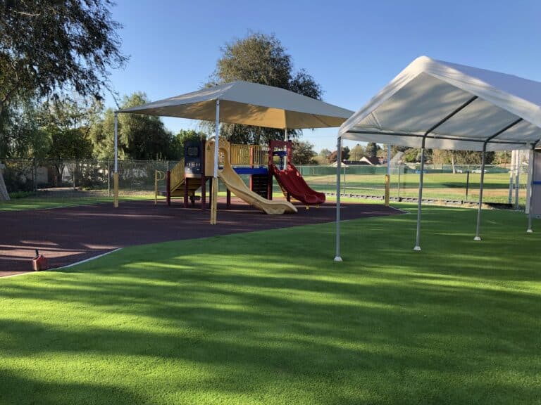 Shade structures over a synthetic turf playground with play equipment