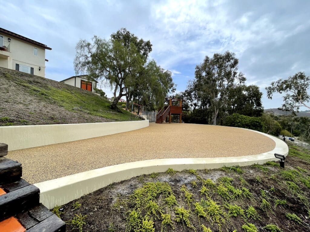 Curving porous rubber pathway with a concrete border through a landscaped slope