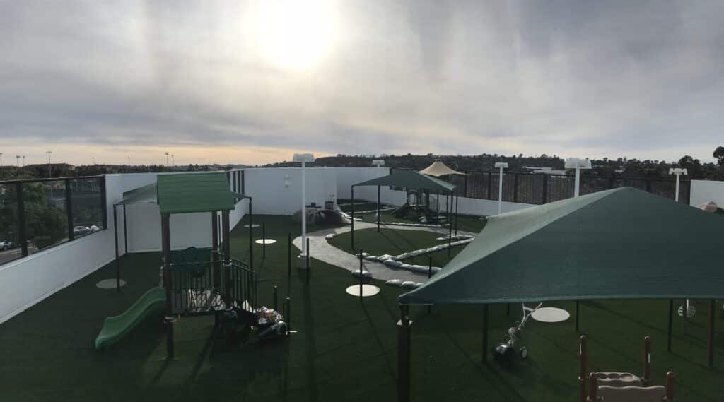 Wide view of shade sails over a playground and turf area