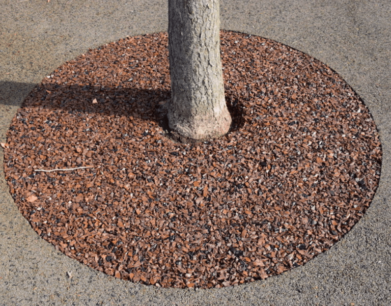 Brown recycled rubber surface filling a tree well around a tree trunk